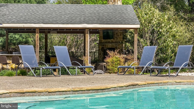 outdoor pool featuring a patio, a gazebo, and an outdoor stone fireplace