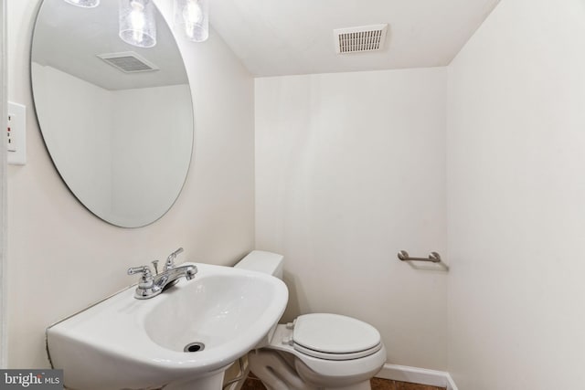 bathroom with toilet, a sink, visible vents, and baseboards