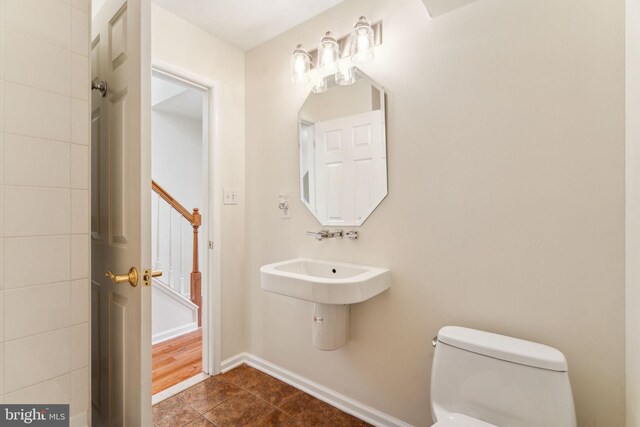 bathroom with tile patterned flooring, baseboards, a sink, and toilet