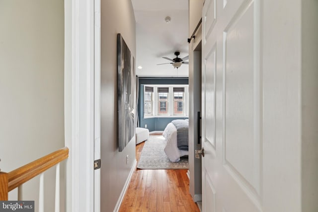 hallway featuring light wood finished floors and baseboards