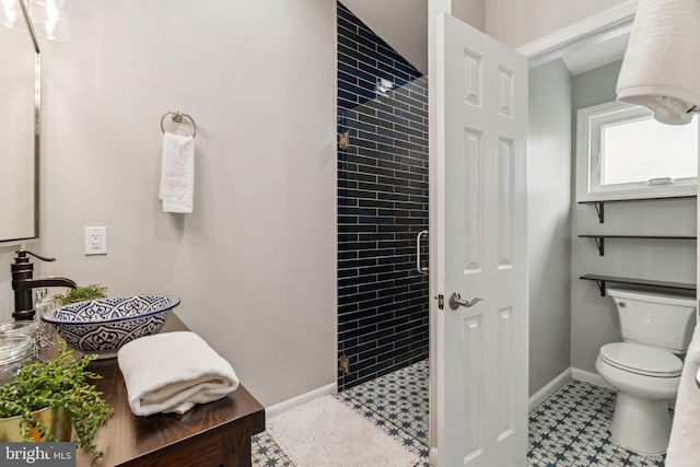 bathroom with baseboards, toilet, tile patterned floors, and a stall shower