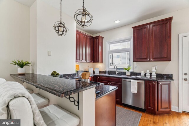 kitchen featuring a peninsula, dark brown cabinets, dishwasher, and a sink