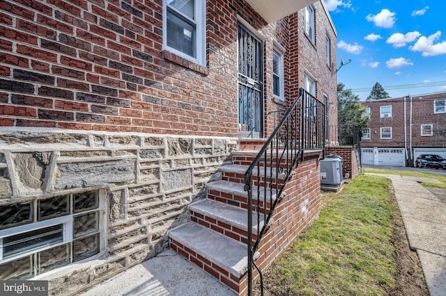 doorway to property featuring brick siding and central AC