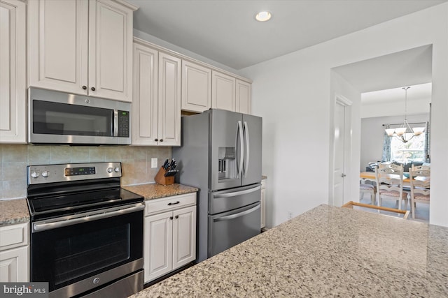 kitchen featuring light stone counters, decorative backsplash, stainless steel appliances, a notable chandelier, and recessed lighting