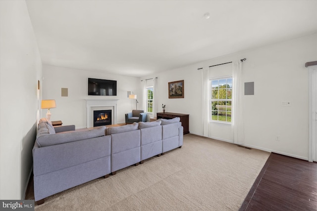 living room featuring visible vents, baseboards, light wood-style flooring, and a glass covered fireplace
