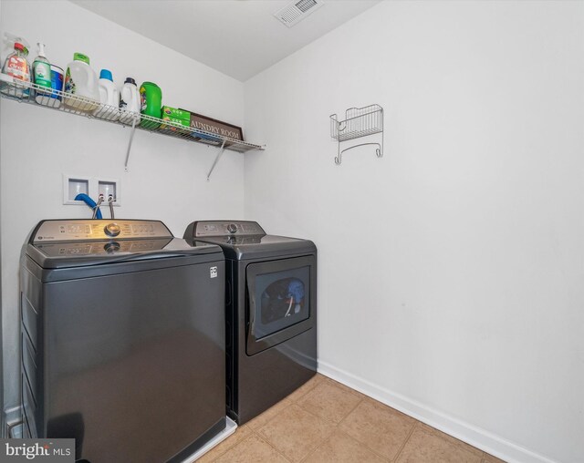 laundry area featuring laundry area, visible vents, light tile patterned flooring, independent washer and dryer, and baseboards
