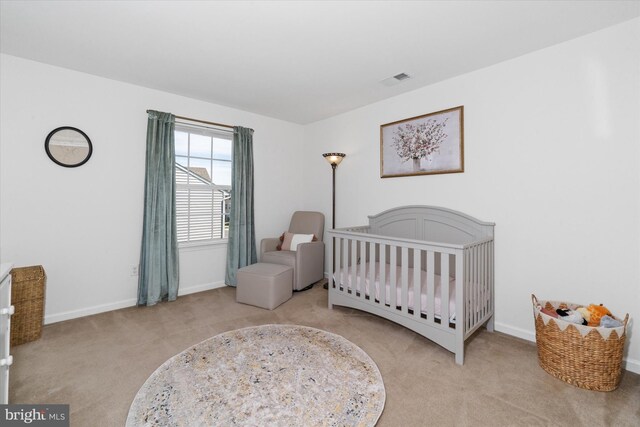 bedroom featuring baseboards, a crib, visible vents, and carpet