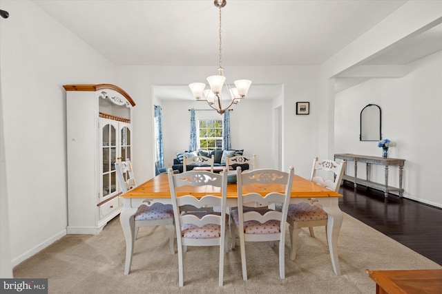dining room featuring a chandelier, baseboards, and light colored carpet
