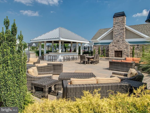 view of patio / terrace featuring outdoor dry bar, an outdoor living space with a fireplace, a gazebo, and fence