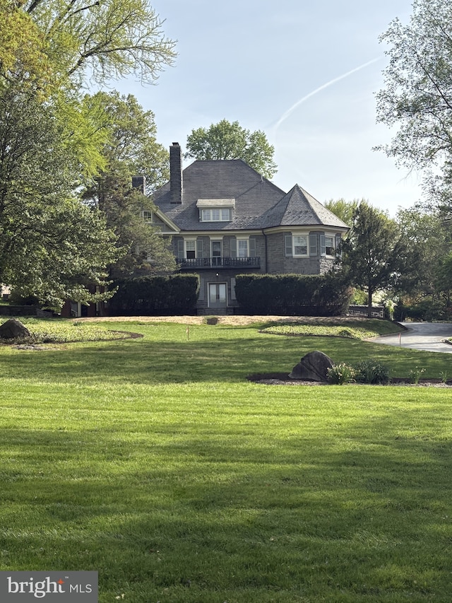view of front facade featuring a chimney and a front lawn