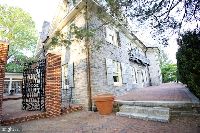 2203 N Grant Ave, Wilmington, DE 19806 - view of side of property with a chimney, a gate, stone siding, and a balcony