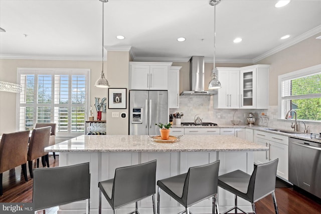kitchen featuring a sink, appliances with stainless steel finishes, white cabinets, and wall chimney range hood