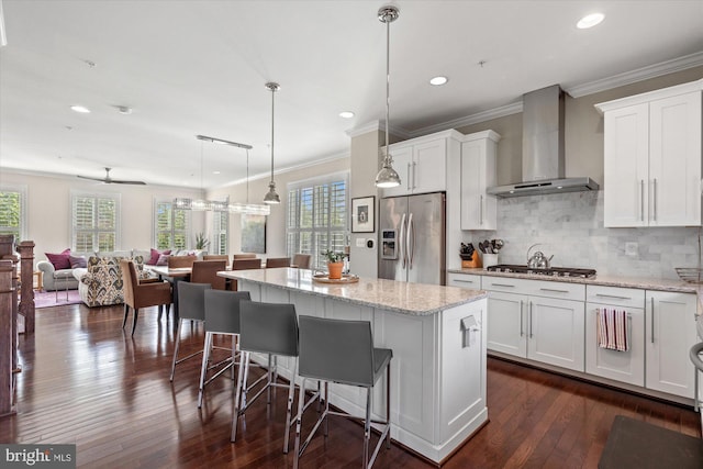 kitchen with stainless steel appliances, plenty of natural light, wall chimney exhaust hood, and a center island