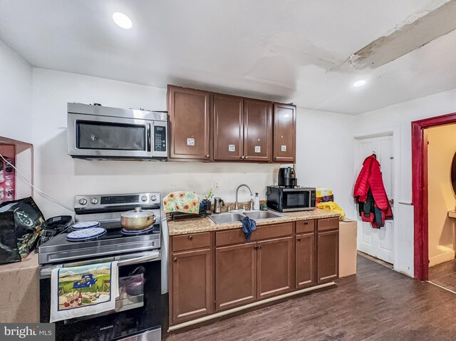 kitchen featuring recessed lighting, a sink, light countertops, appliances with stainless steel finishes, and dark wood-style floors