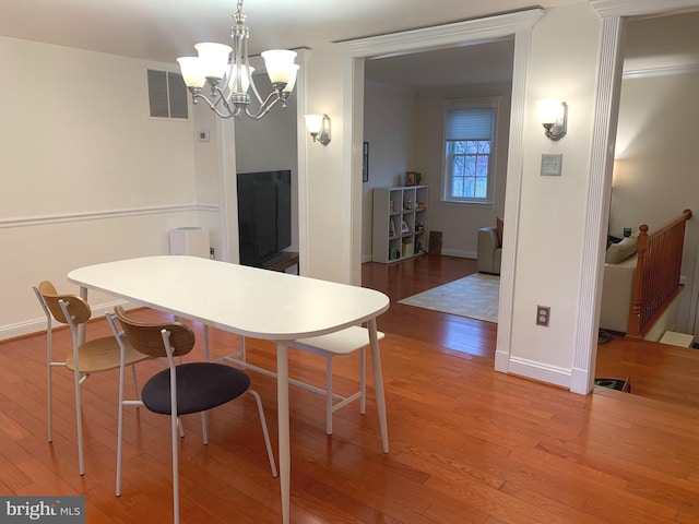 dining room featuring baseboards, visible vents, hardwood / wood-style flooring, and a notable chandelier