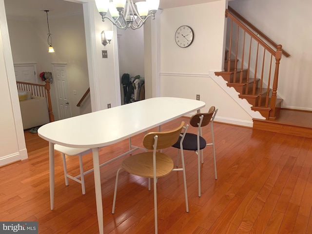 dining space with stairway, light wood-style floors, a notable chandelier, and baseboards