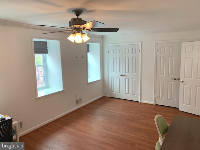 interior space featuring crown molding, visible vents, baseboards, wood finished floors, and a ceiling fan