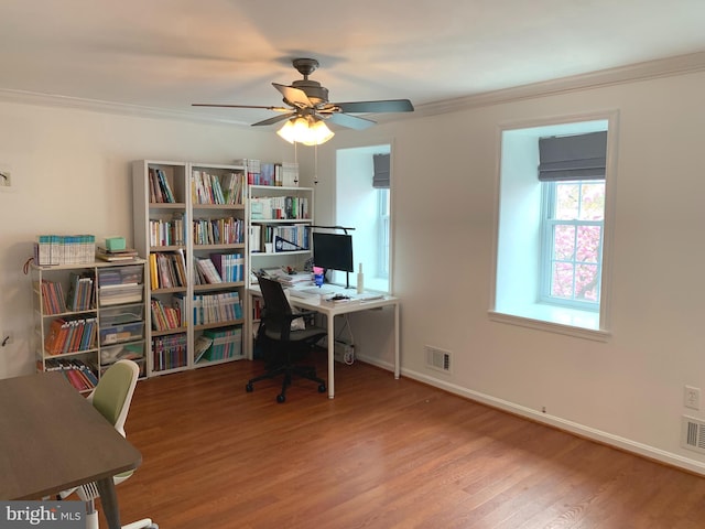 office area featuring wood finished floors, ceiling fan, baseboards, visible vents, and crown molding