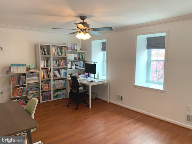 office featuring visible vents, baseboards, ornamental molding, wood finished floors, and a ceiling fan