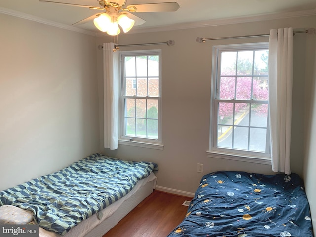 bedroom featuring crown molding, multiple windows, wood finished floors, and baseboards