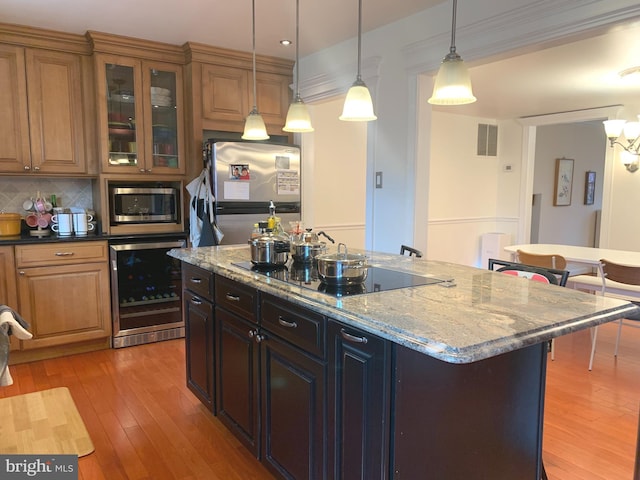 kitchen with decorative backsplash, light wood-style floors, stainless steel appliances, pendant lighting, and beverage cooler