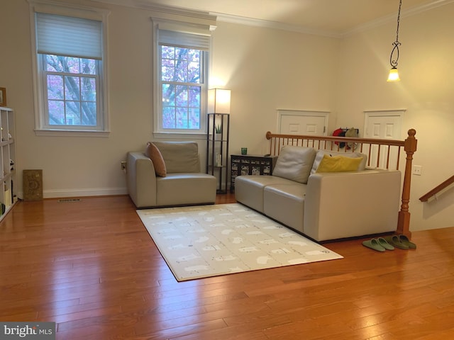 living room with baseboards, visible vents, ornamental molding, and hardwood / wood-style flooring