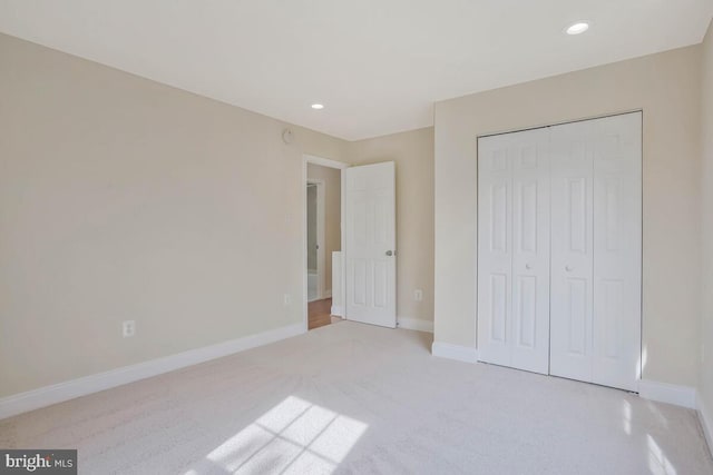 unfurnished bedroom with baseboards, recessed lighting, a closet, and light carpet