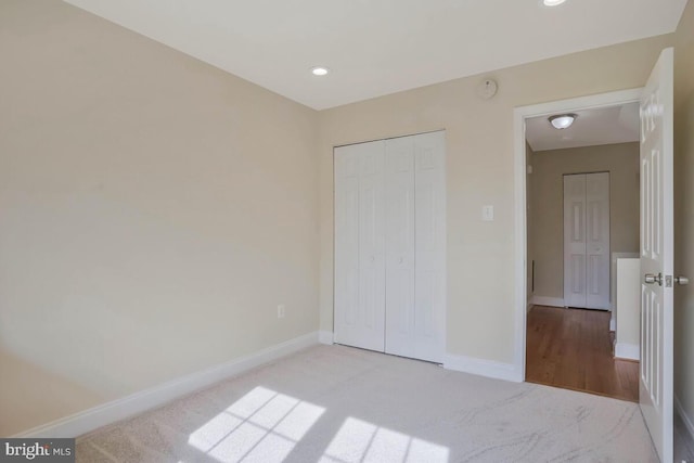 unfurnished bedroom featuring baseboards, carpet flooring, recessed lighting, and a closet