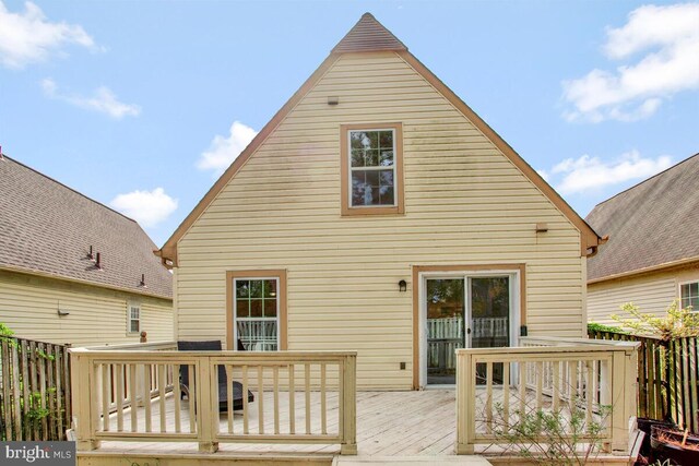back of property with fence and a deck