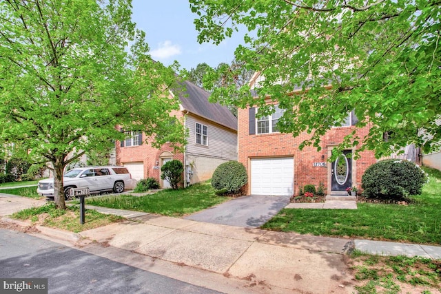 view of front facade featuring a garage, driveway, a front lawn, and brick siding