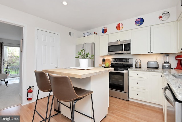 23 Academy Ct, Pennington, NJ 08534 - kitchen with butcher block counters, a breakfast bar, appliances with stainless steel finishes, white cabinets, and visible vents
