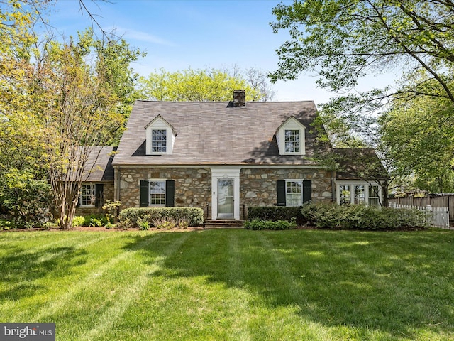 cape cod house with a chimney, a front lawn, and stone siding