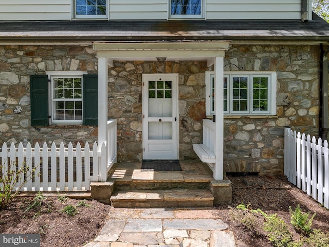 entrance to property with fence and stone siding