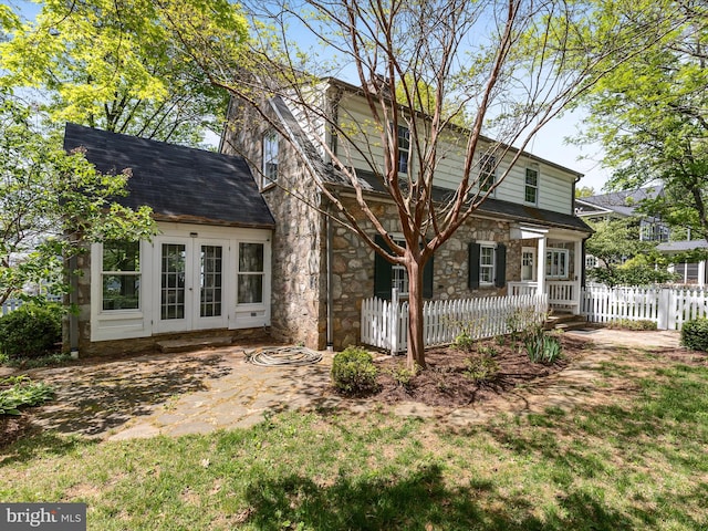 exterior space featuring french doors, fence, and stone siding