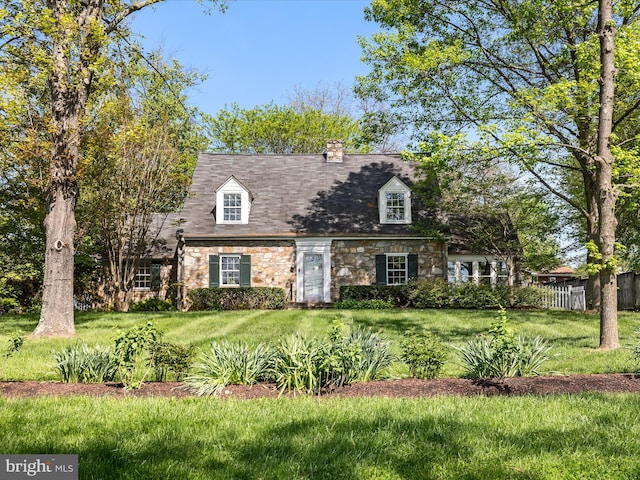 cape cod home featuring fence, a chimney, a front lawn, and stone siding