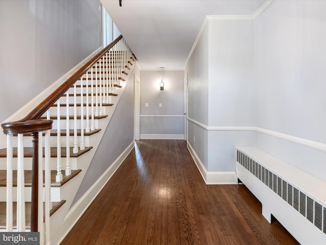 hall featuring crown molding, wood finished floors, baseboards, radiator heating unit, and stairs