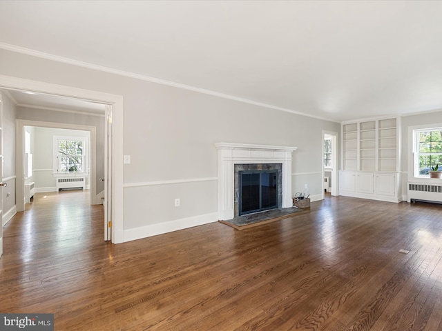 unfurnished living room featuring radiator heating unit, crown molding, a premium fireplace, and dark wood-type flooring