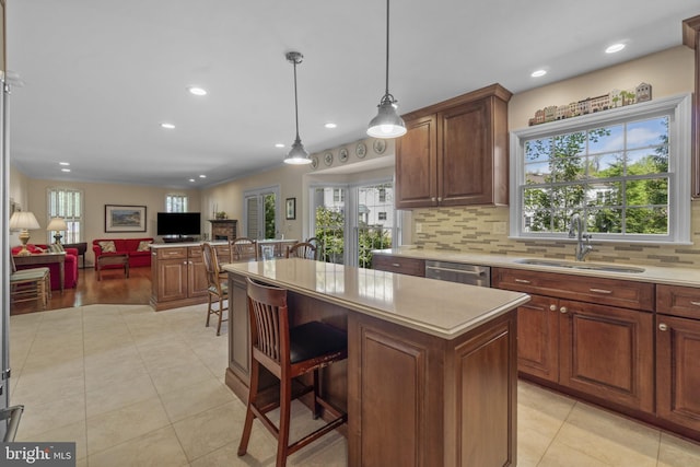 kitchen with a sink, light countertops, recessed lighting, stainless steel dishwasher, and a kitchen island