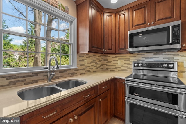 kitchen with tasteful backsplash, a sink, light countertops, stainless steel appliances, and a wealth of natural light