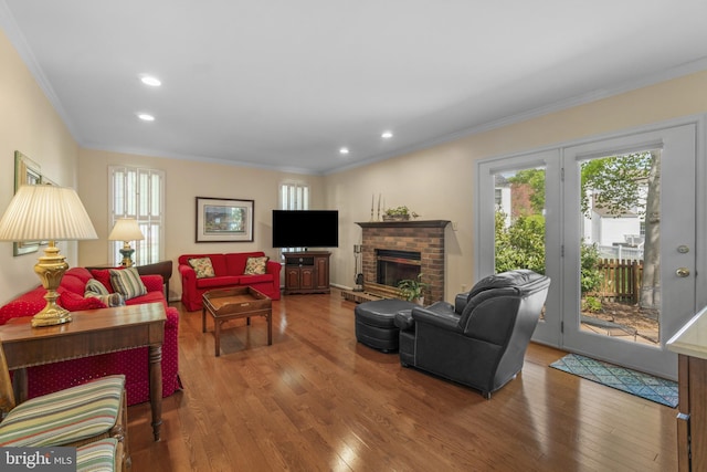 living area featuring crown molding, wood finished floors, and a healthy amount of sunlight