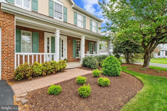 doorway to property with brick siding and a porch