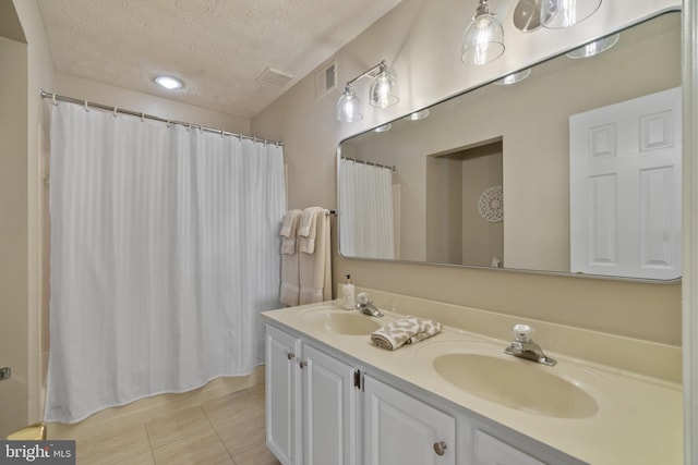 full bathroom with visible vents, a sink, a textured ceiling, and tile patterned flooring