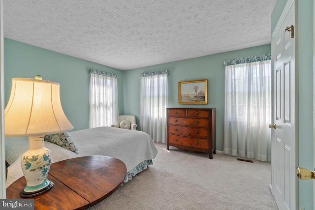 carpeted bedroom with a textured ceiling and visible vents