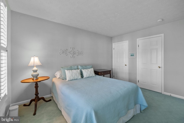 bedroom with a textured ceiling, baseboards, and carpet