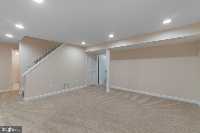 finished below grade area with baseboards, light carpet, and visible vents