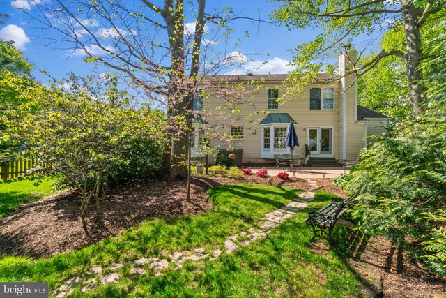 rear view of house with entry steps, a chimney, a patio area, and french doors