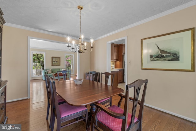dining room featuring crown molding, baseboards, a notable chandelier, and light wood-style flooring