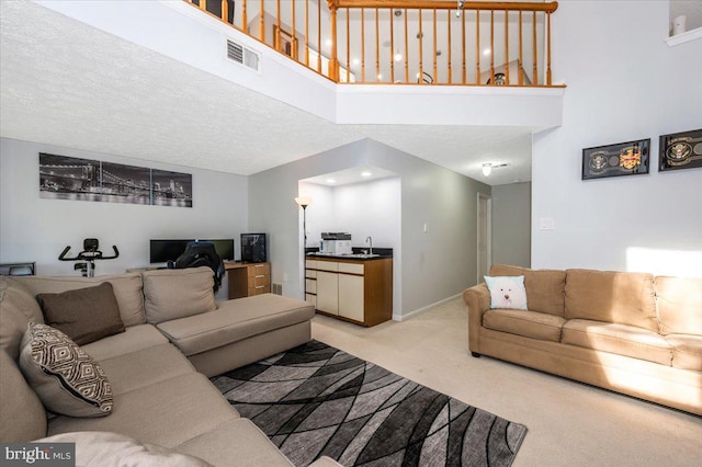 living area featuring a towering ceiling, visible vents, light carpet, and baseboards