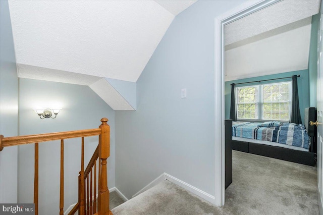 interior space with an upstairs landing, vaulted ceiling, carpet, and baseboards
