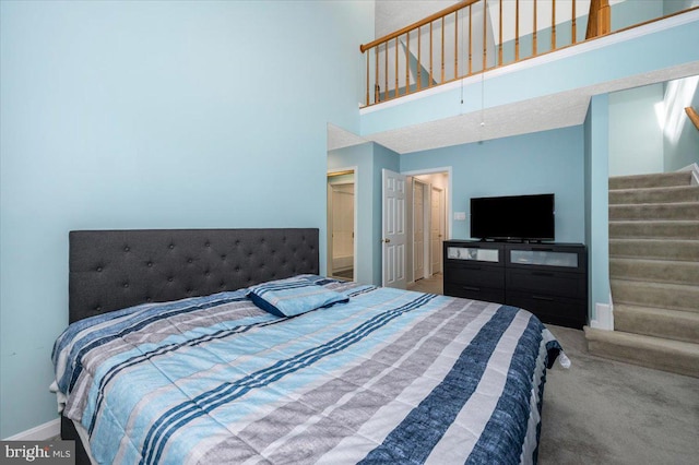 carpeted bedroom featuring baseboards and a high ceiling